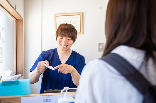 整体院の院長 山口朋宏が患者さんに優しい笑顔で接客している写真