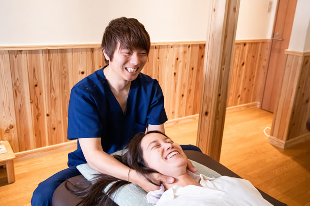 Correct整体院の院長 山口朋宏が患者さんに笑顔で施術している写真
